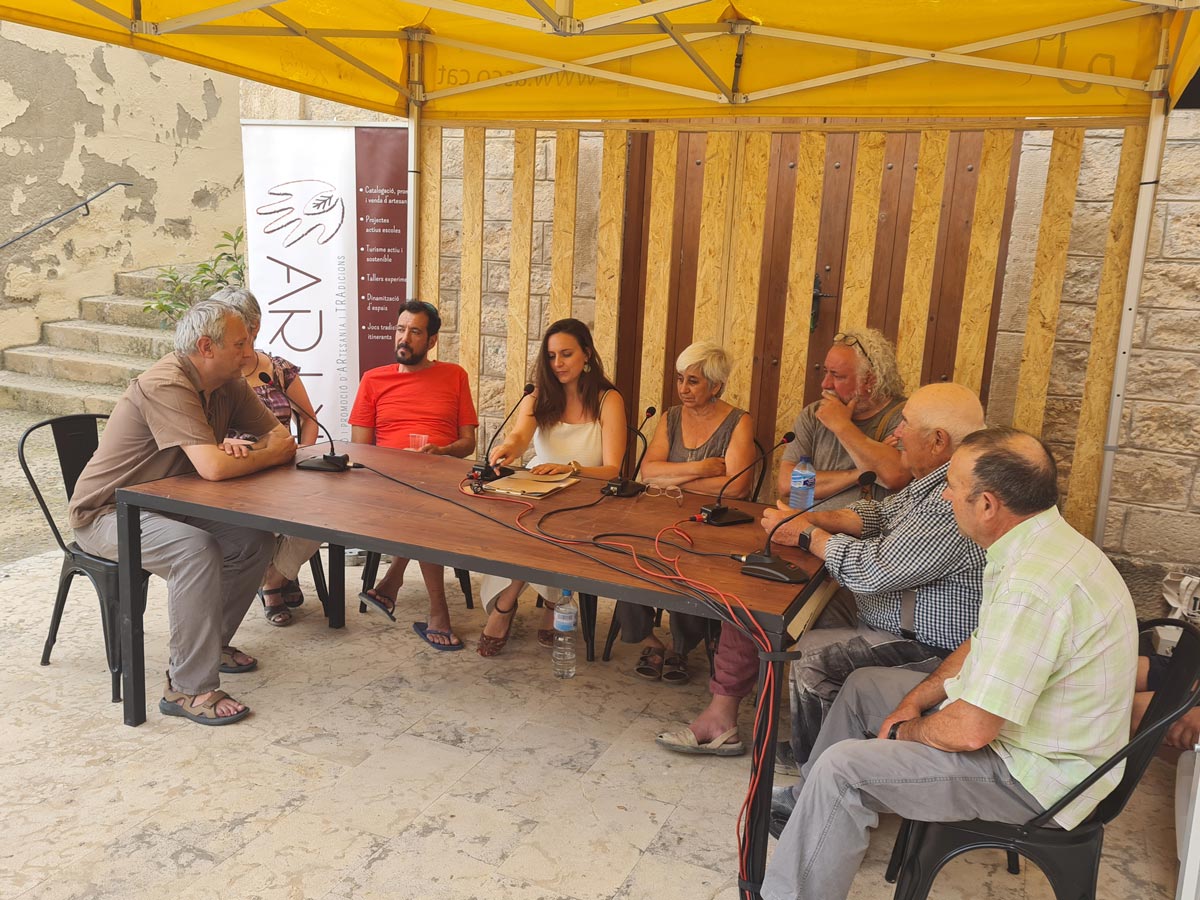 Coferencia Conferència on es poden veure 8 participants baix d'una carpa groga.