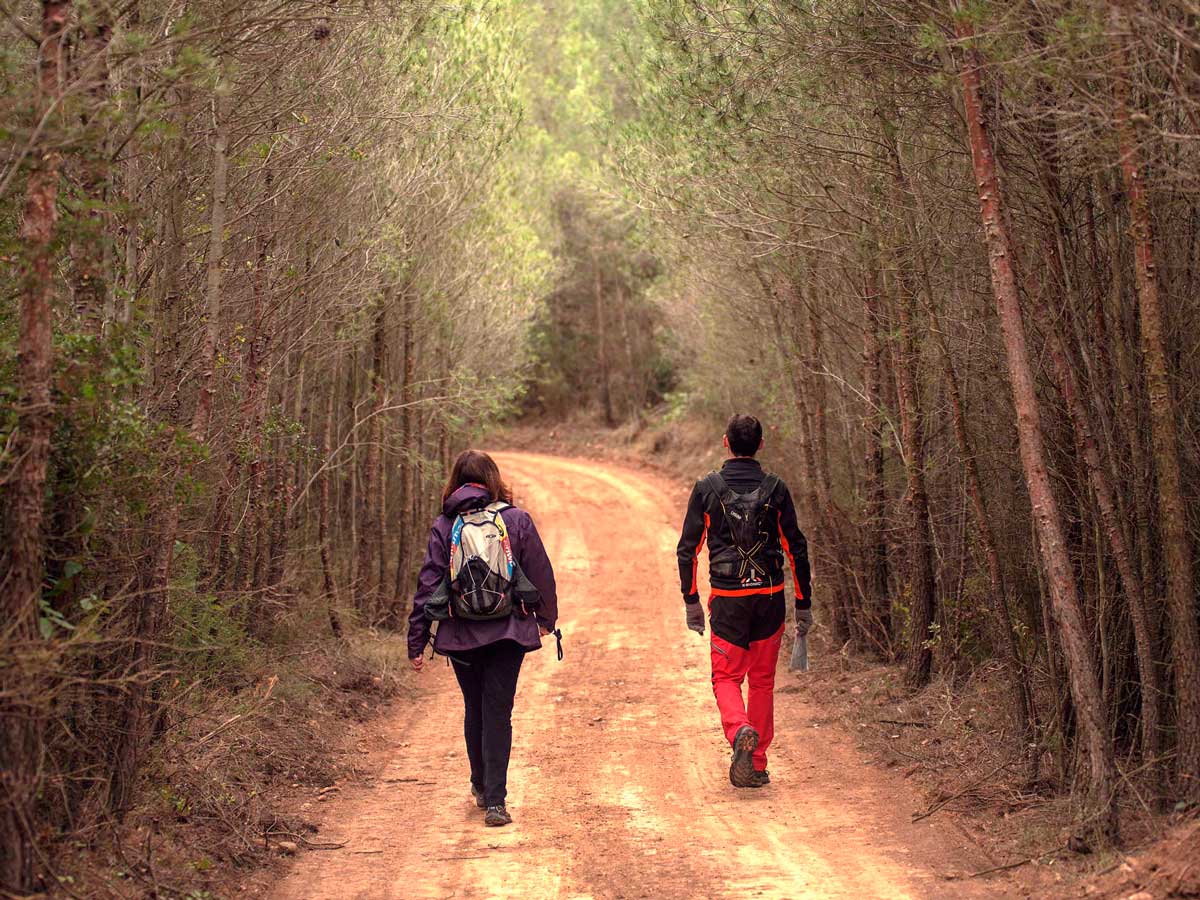 Fotografia amb un noi i una noia caminant per un camí de terra