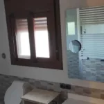 Lavabo on hi ha una pica, un espill i una finestra petita.