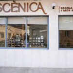 Façana de "Le’scènica, Escola de Dansa i Arts Escèniques" on es veu el logotip amb acabat fusta i dues finestres, una més gran i l'altra més petita.