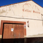 Façana del Celler Serra on es veu el logotip i una porta gran de fusta.