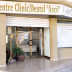 Façana de la Clínica Dental d'Ascó on hi ha una porta de vidre i rètols amb informació del negoci.