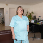 Fotografia de l'interior de la Clínica Dental on al centre hi ha una dona mirant a càmera somrient.